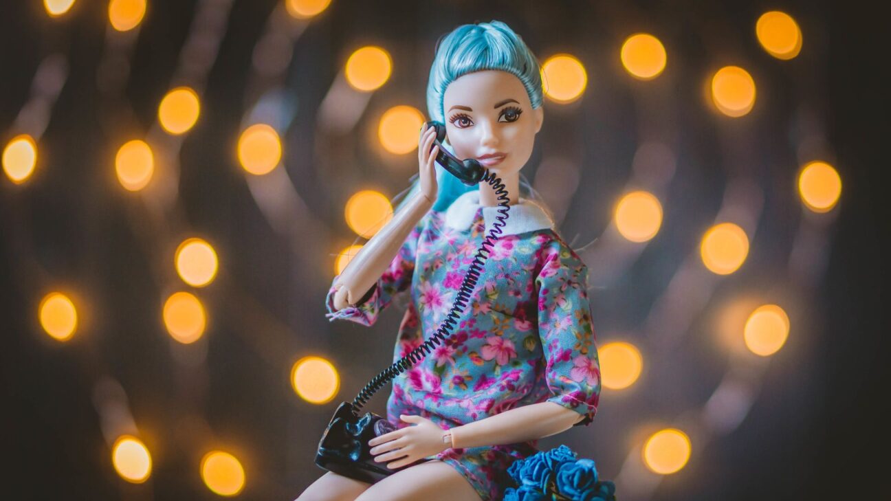 A Barbie doll with blue hair holds a telephone