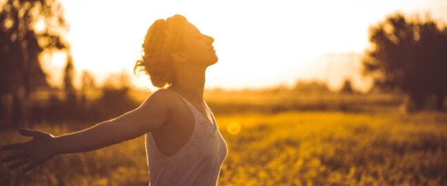 A woman taking a breath in a field outdoors